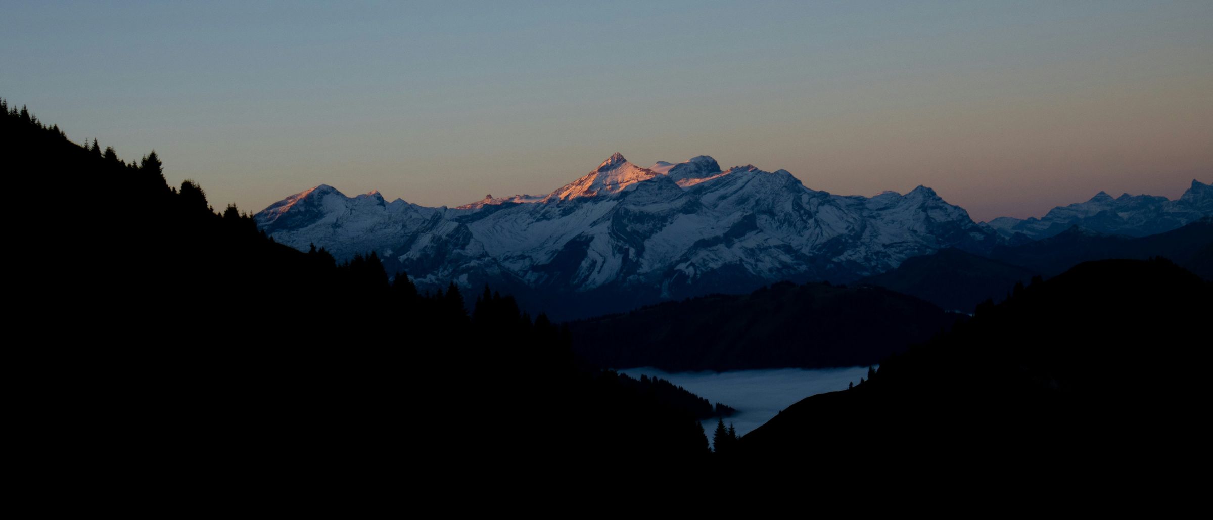 Lumière du soir sur les montagnes au-dessus d’une mer de brouillard dans le Saanenland